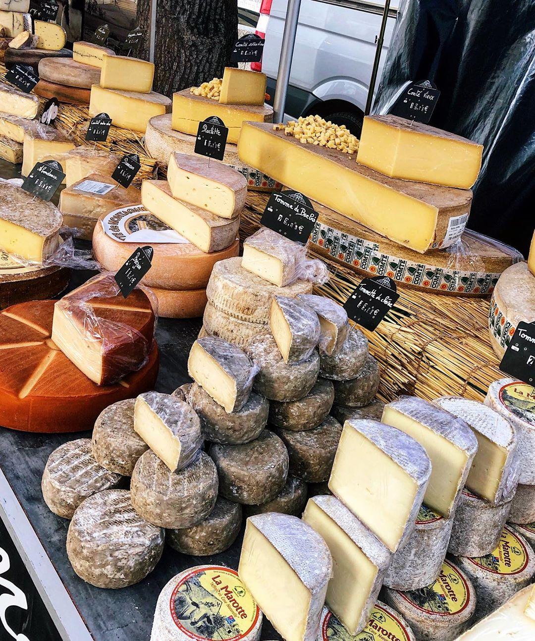 Wheels of Comté and Tomme cheese on a French market stall