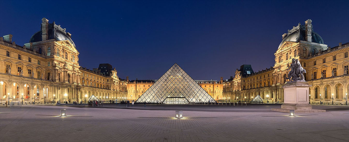 The Louvre Museum and glass pyramid illuminated at dusk